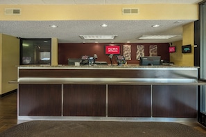 A hotel reception desk with a digital clock, a 'Free Wi-Fi All Rooms' sign, and a Lenovo computer monitor. - Red Roof Inn PLUS+ Wilmington - Newark (Newark)