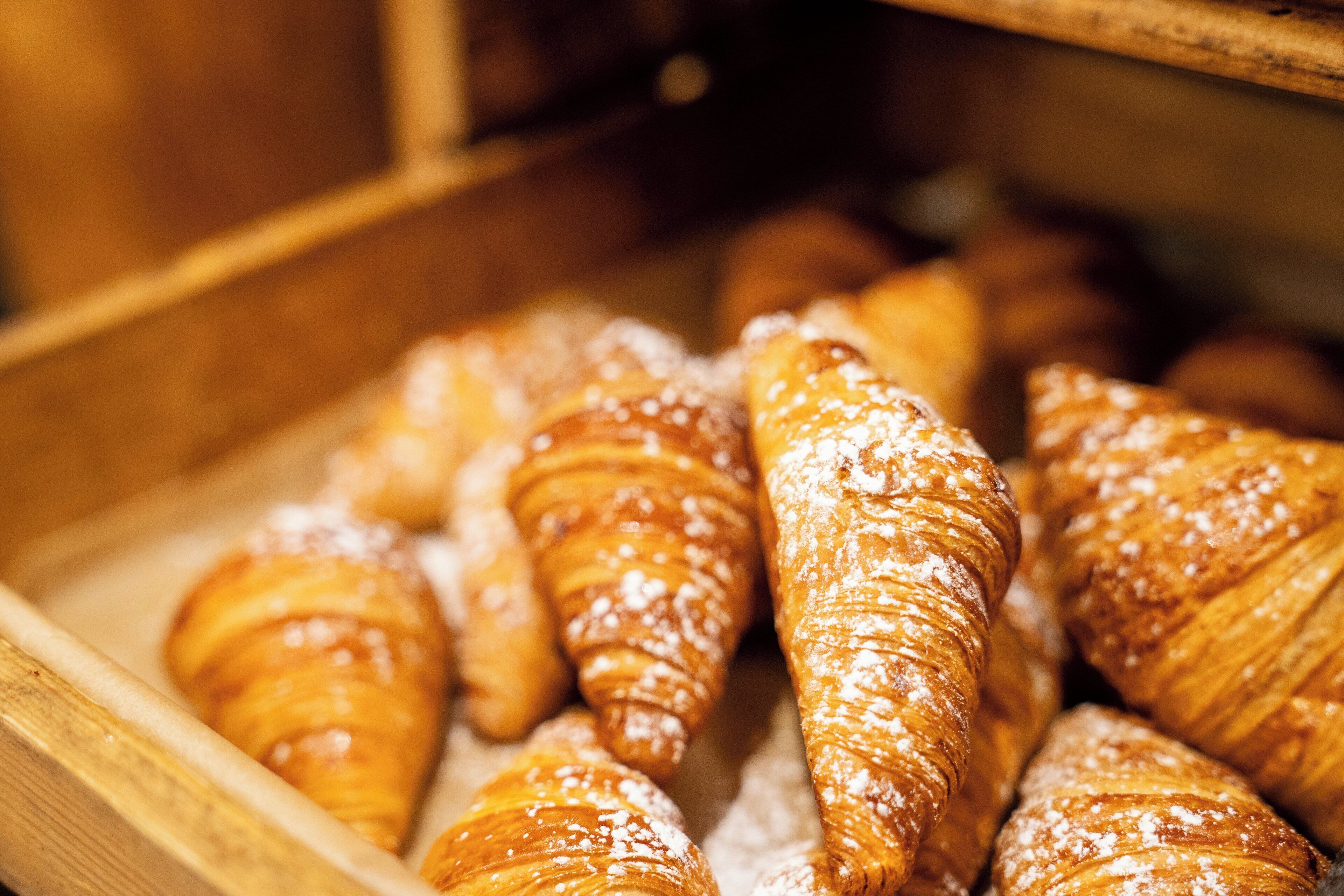 A wooden tray filled with various pastries, including croissants and other baked goods.