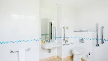 A modern bathroom with a sink, mirror, toilet, and handrails.