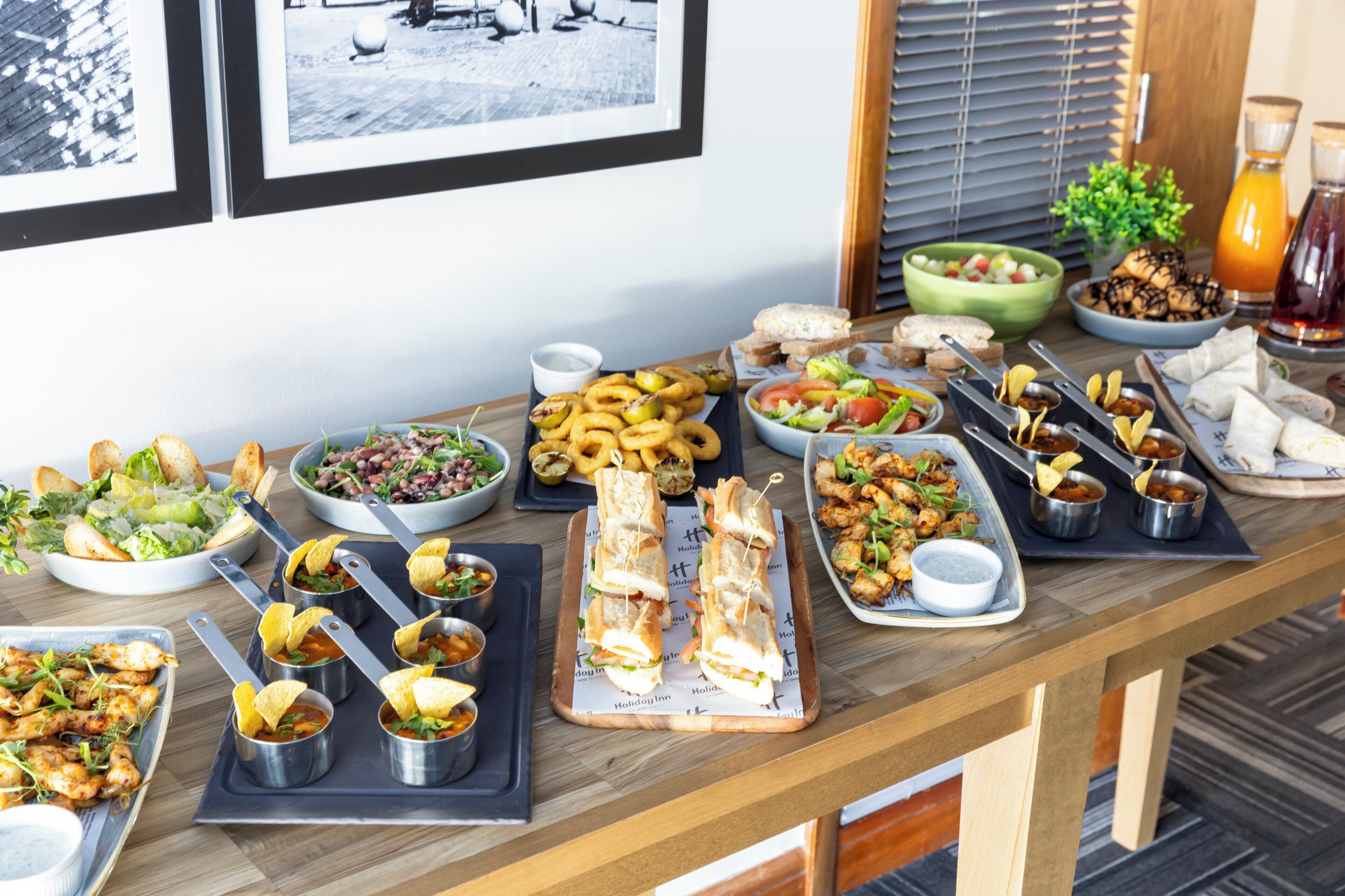 A buffet table with various dishes including salads, sandwiches, and appetizers.