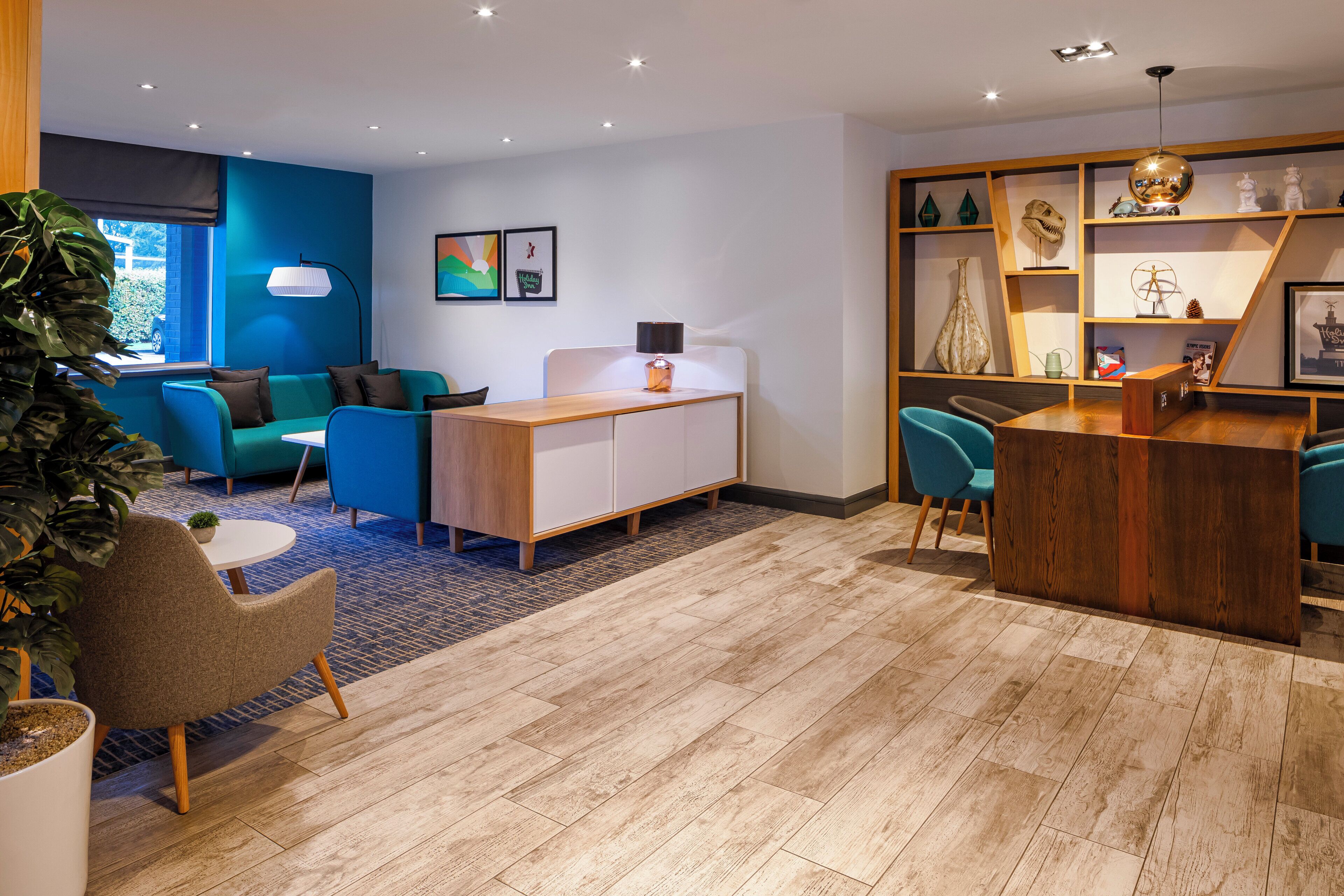 A modern living room with a wooden coffee table, teal sofas, and a wooden cabinet.