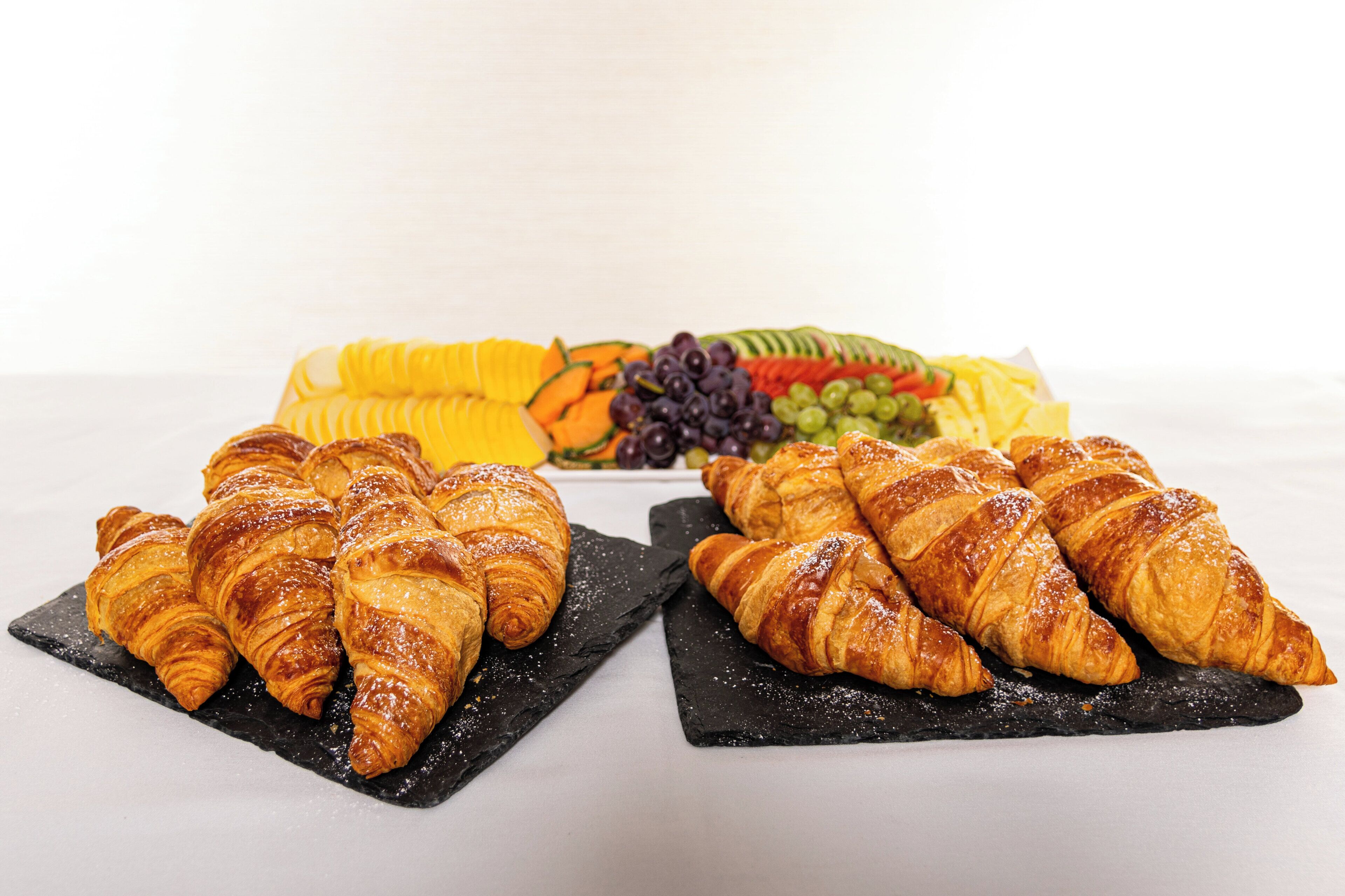A table with croissants and a fruit platter.