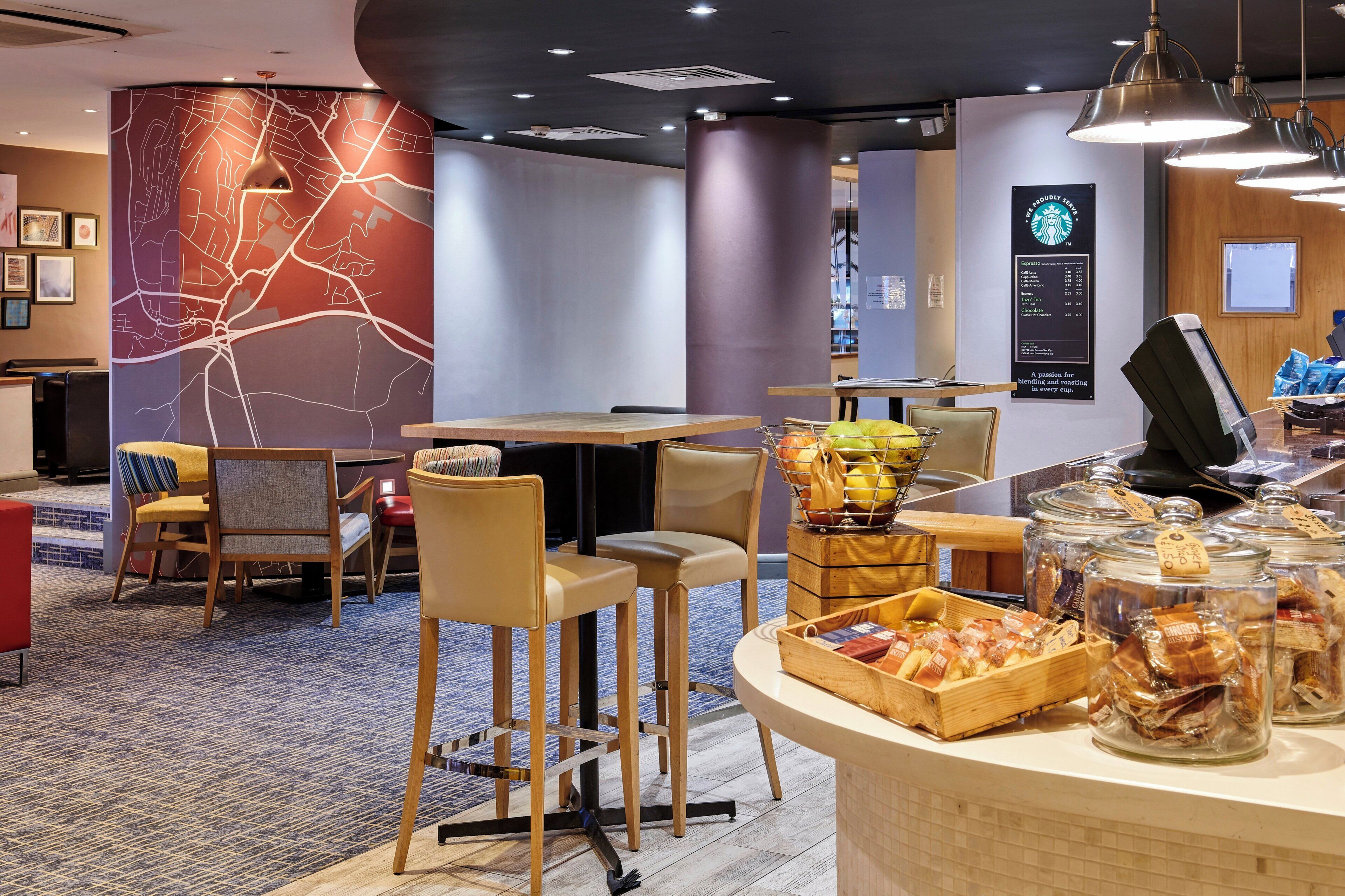 A hotel lobby with a bar area, seating arrangements, and a wall with a cityscape design.