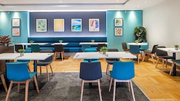 A modern dining area with blue and white furniture, a central seating area, and artwork on the walls.