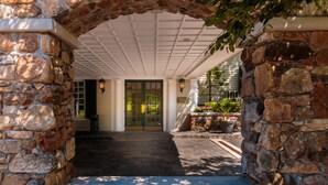 A stone archway leading to a covered entrance with a bench. - Olde Mill Inn (Basking Ridge)