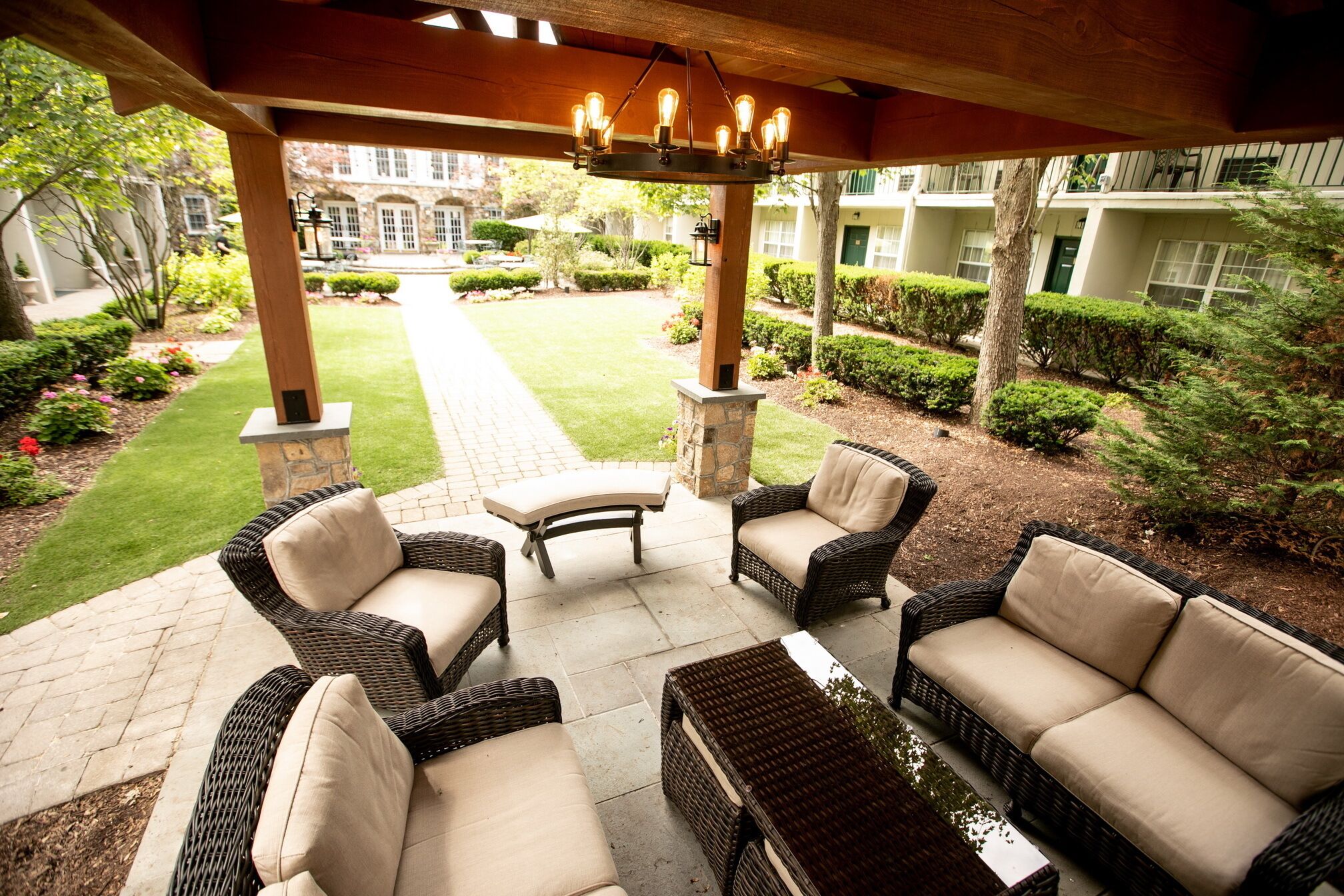 A covered outdoor seating area with wicker furniture and a stone pillar.