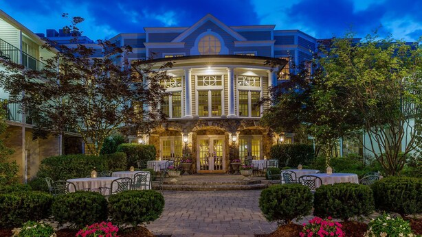 A large, elegant building with a grand entrance, a well-maintained garden, and outdoor seating areas. - Olde Mill Inn (Basking Ridge)