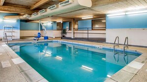 An indoor swimming pool with clear blue water, wooden ceiling beams, and a blue and white tiled floor. - Comfort Inn Marshalltown South (Marshalltown)