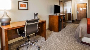 A hotel room with a desk, chair, television, and a bed. - Comfort Inn Marshalltown South (Marshalltown)