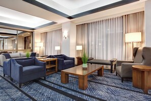 Habitación de hotel con sala de estar que incluye sofás, una mesa de centro y una mesa de comedor.