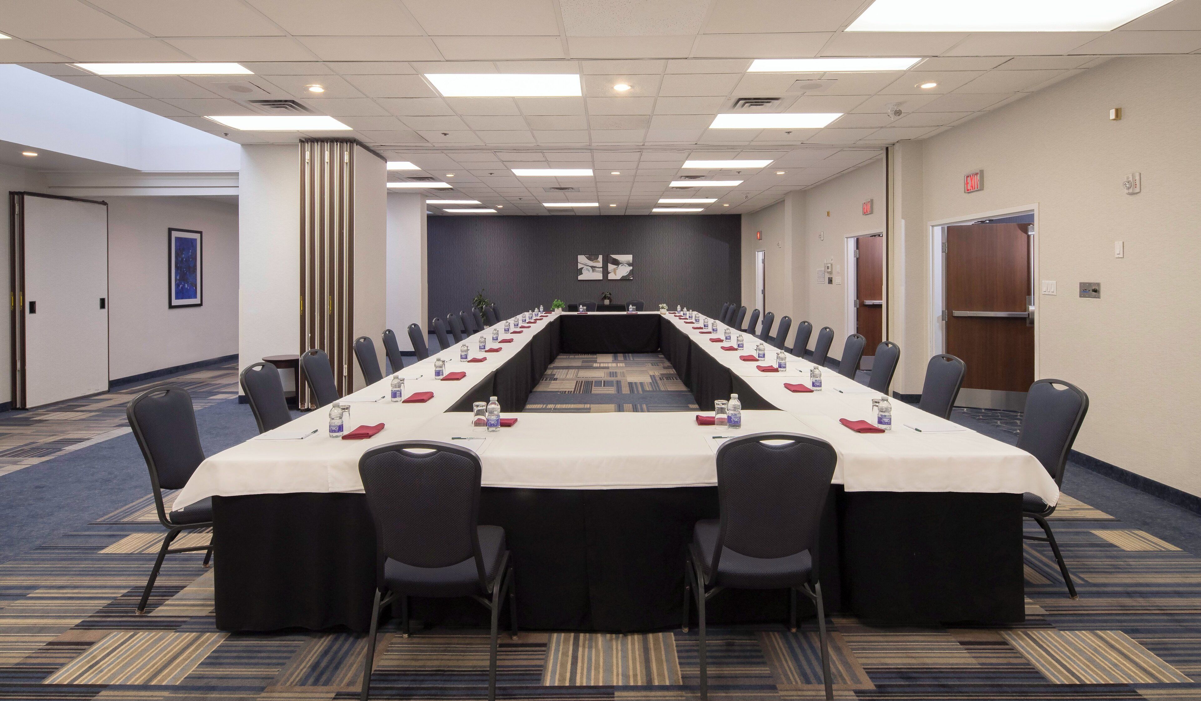 A conference room with a long table, chairs, and water bottles.