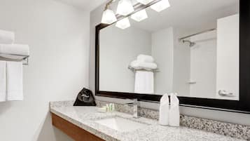 Une salle de bain dotée d’un comptoir en granit, d’un grand miroir et d’un porte-serviettes.