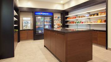 A clean, modern food service area with a Pepsi refrigerator, a Starbucks cooler, and shelves stocked with snacks.