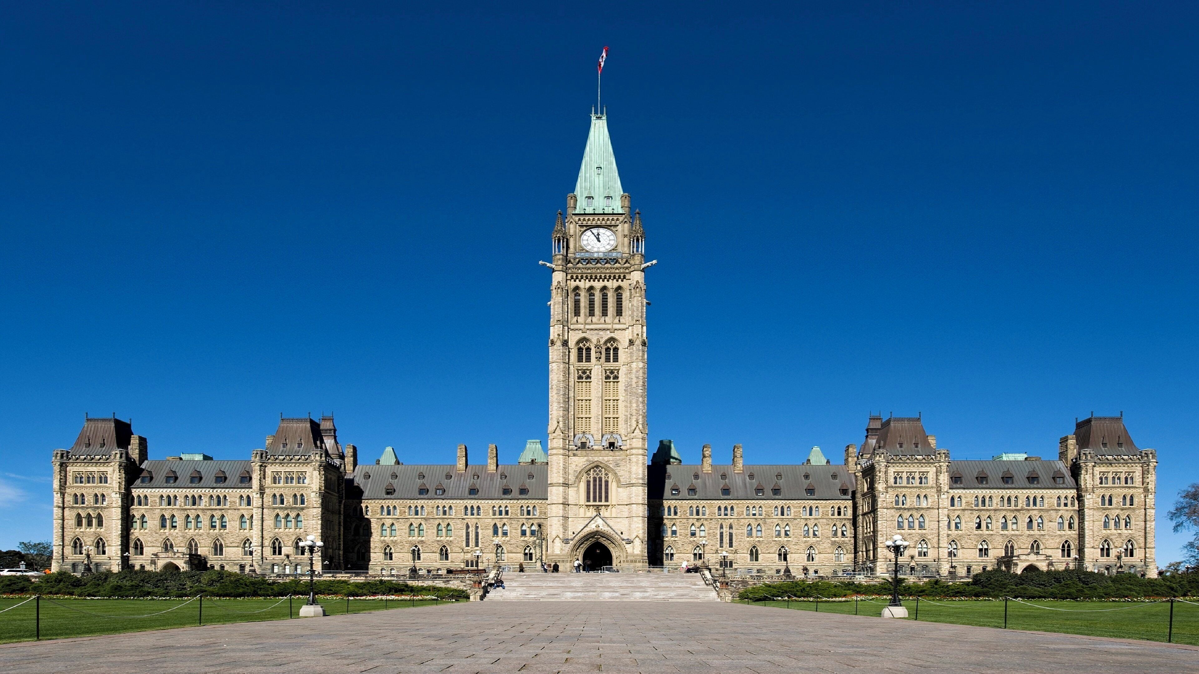 A large, historic building with a prominent clock tower, symmetrical architecture, and a central entrance.
