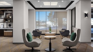 Un moderno hall de entrada con una mesa redonda, dos sillones y una estantería.
