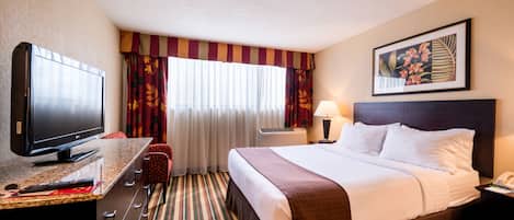 Una habitación de hotel con cama, televisión, escritorio y silla.