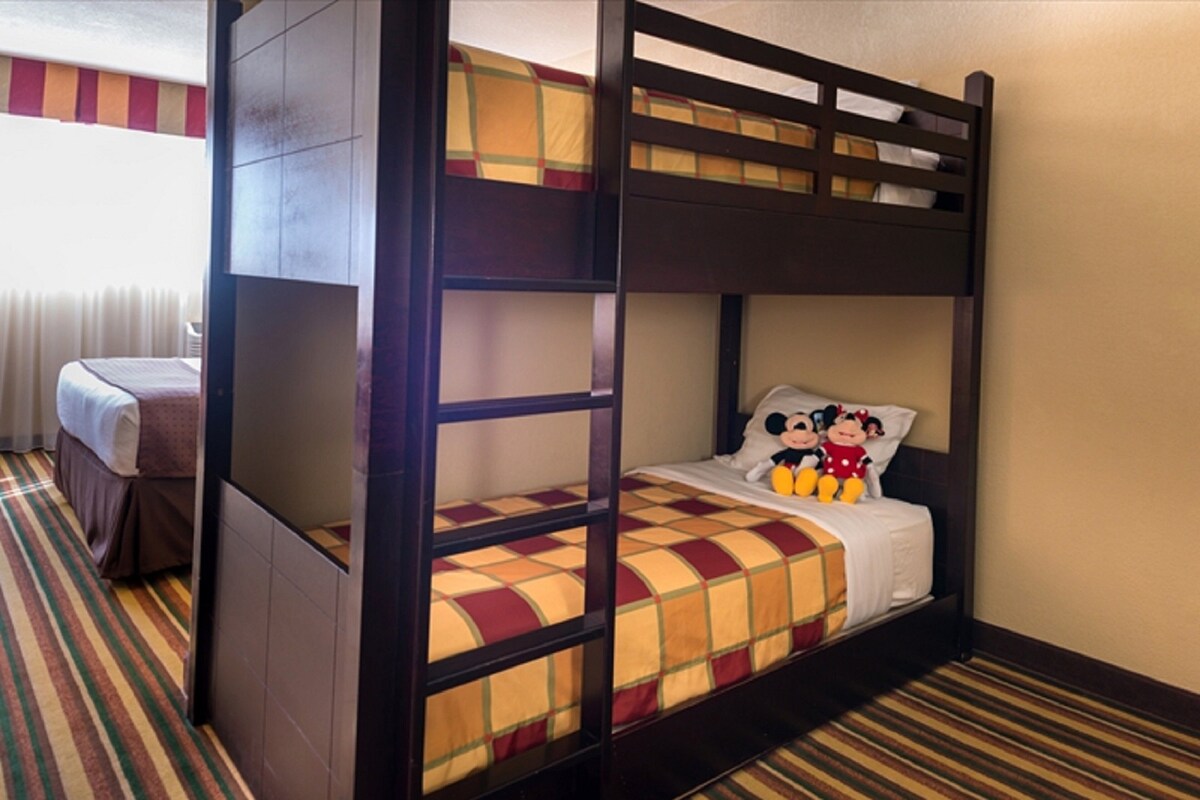 Uma cama beliche com colcha xadrez e bichos de pelúcia do Mickey Mouse.