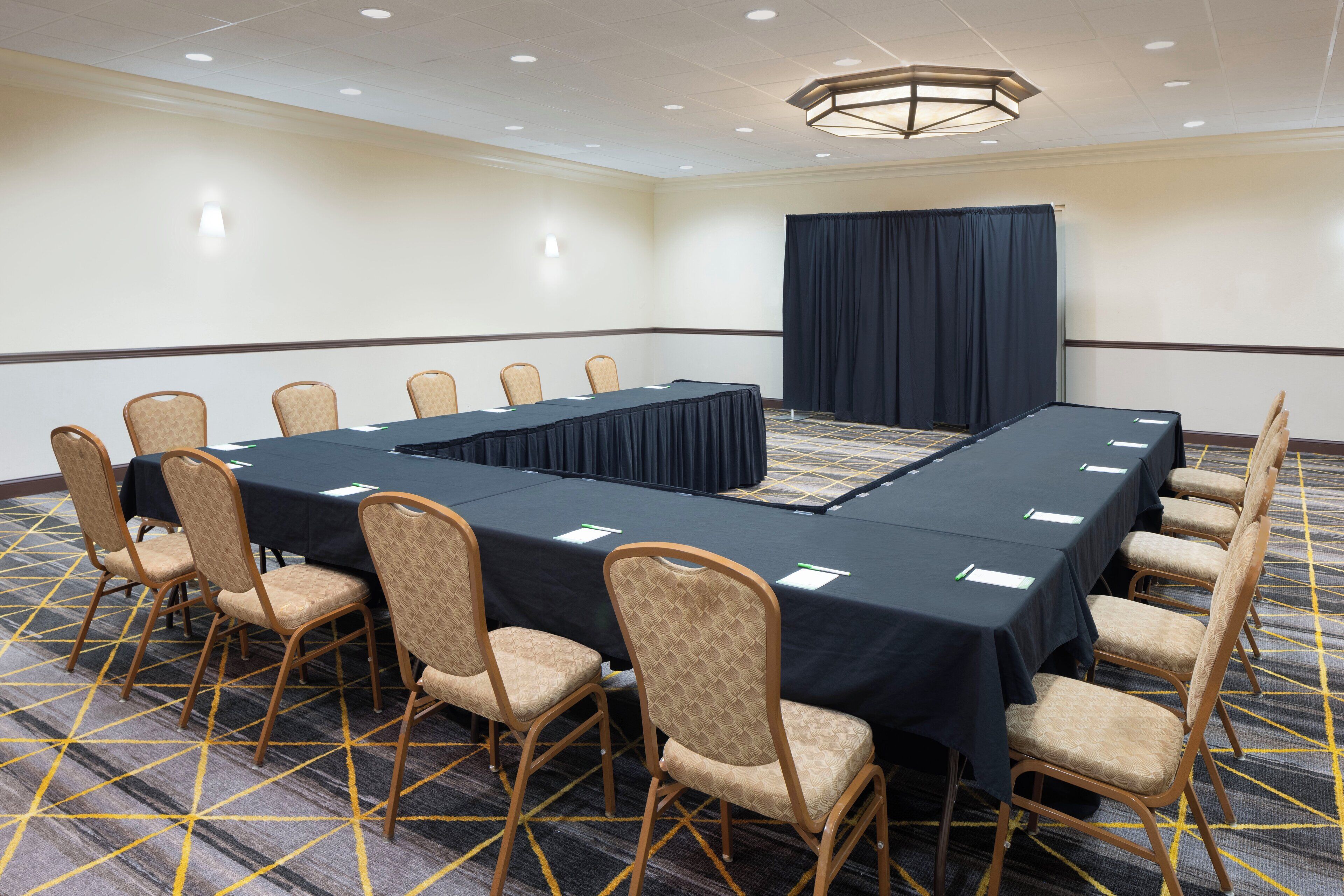 Une salle de conférence avec une longue table, des chaises et un sol recouvert de moquette.