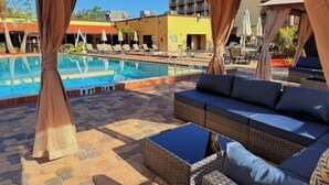 Area piscina con una poltrona da relax, un tavolino e una zona salotto coperta.