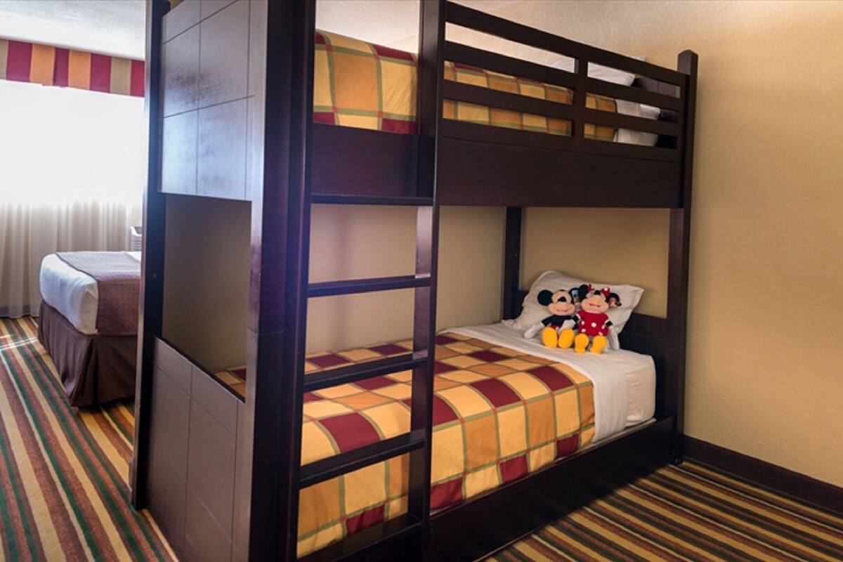 Un letto a castello con copriletto a scacchi e peluche di Topolino.