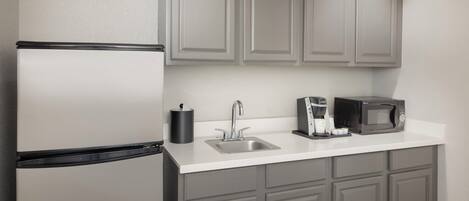 A kitchen with a refrigerator, sink, and microwave.