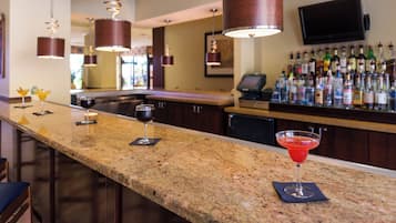 Una zona de bar con encimera de granito, taburetes y una variedad de botellas de licor.