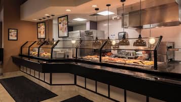 A buffet area with a glass partition, various food items, and overhead lighting.