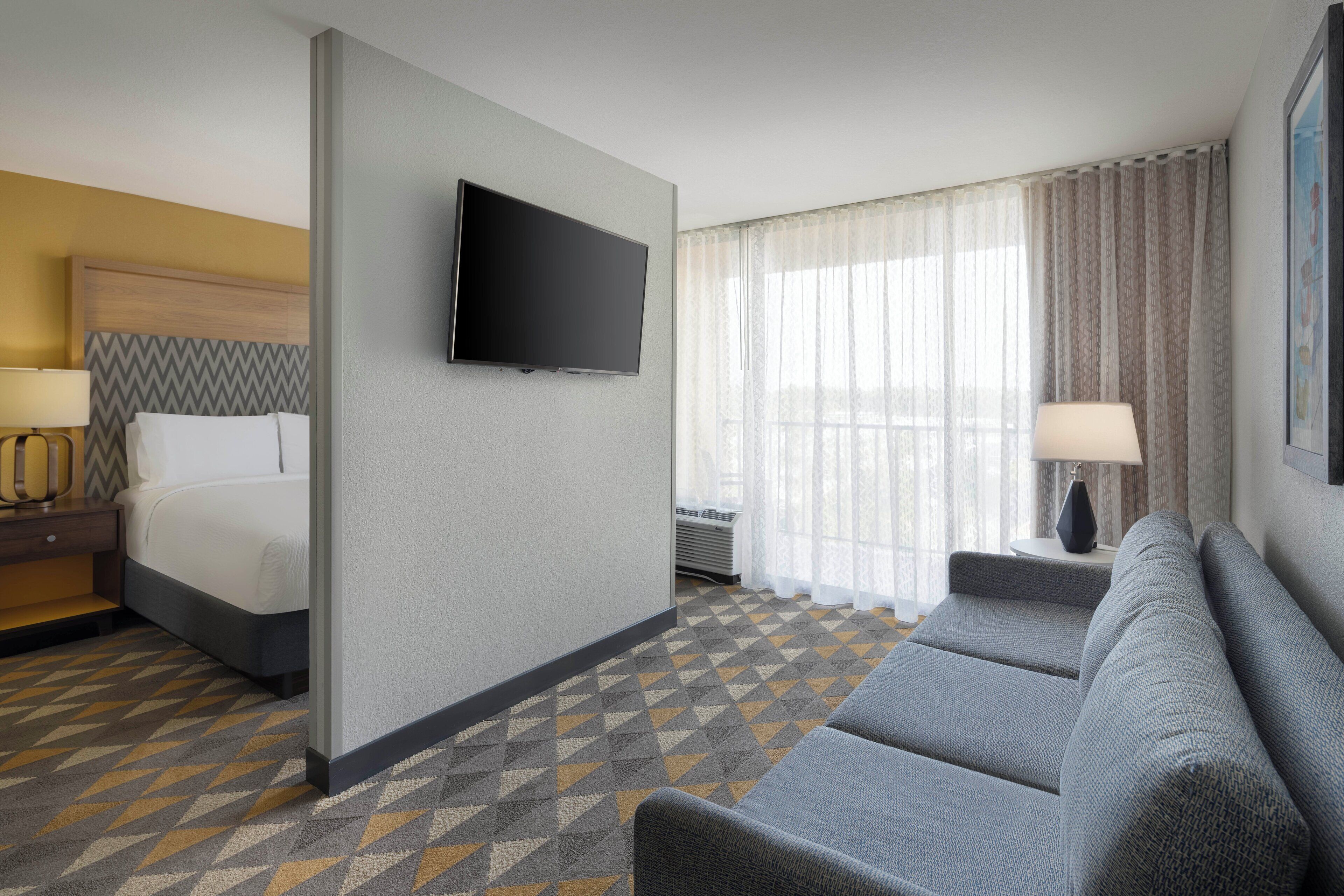 Ein Hotelzimmer mit einem Bett, einem Fernseher, einer Sitzecke und einem gemusterten Teppich.