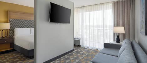 A hotel room with a bed, a TV, a sofa, and a patterned carpet.