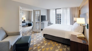 Une chambre d’hôtel avec un lit, un canapé, un bureau, une télévision et une moquette à motifs.