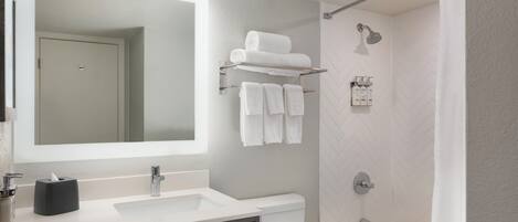A modern bathroom with a large mirror, a sink, a toilet, and a shower.