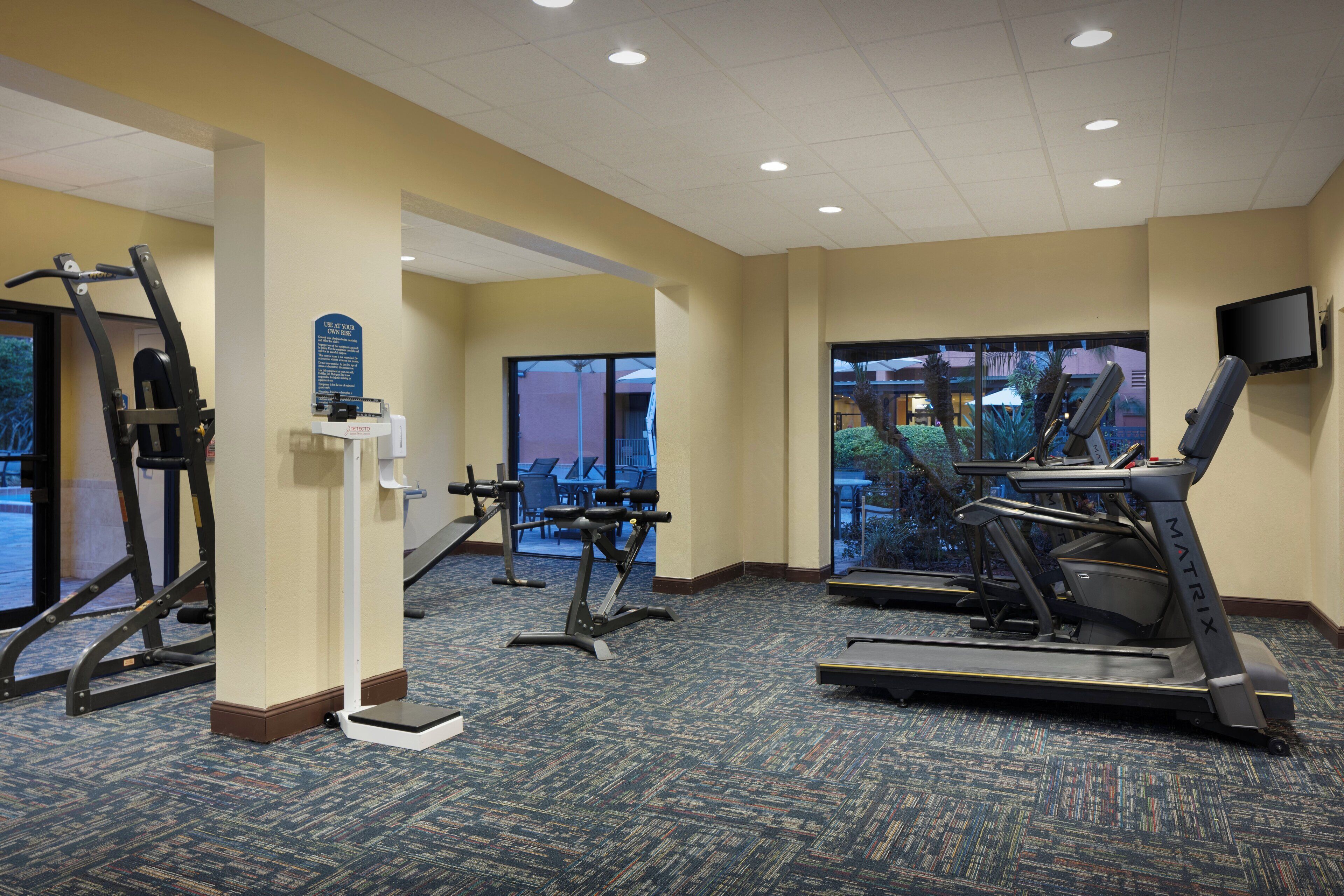 A hotel fitness center with treadmills, elliptical machines, and weight machines.