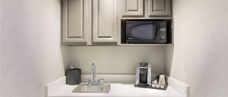 A kitchenette with a microwave, coffee maker, and a sink.