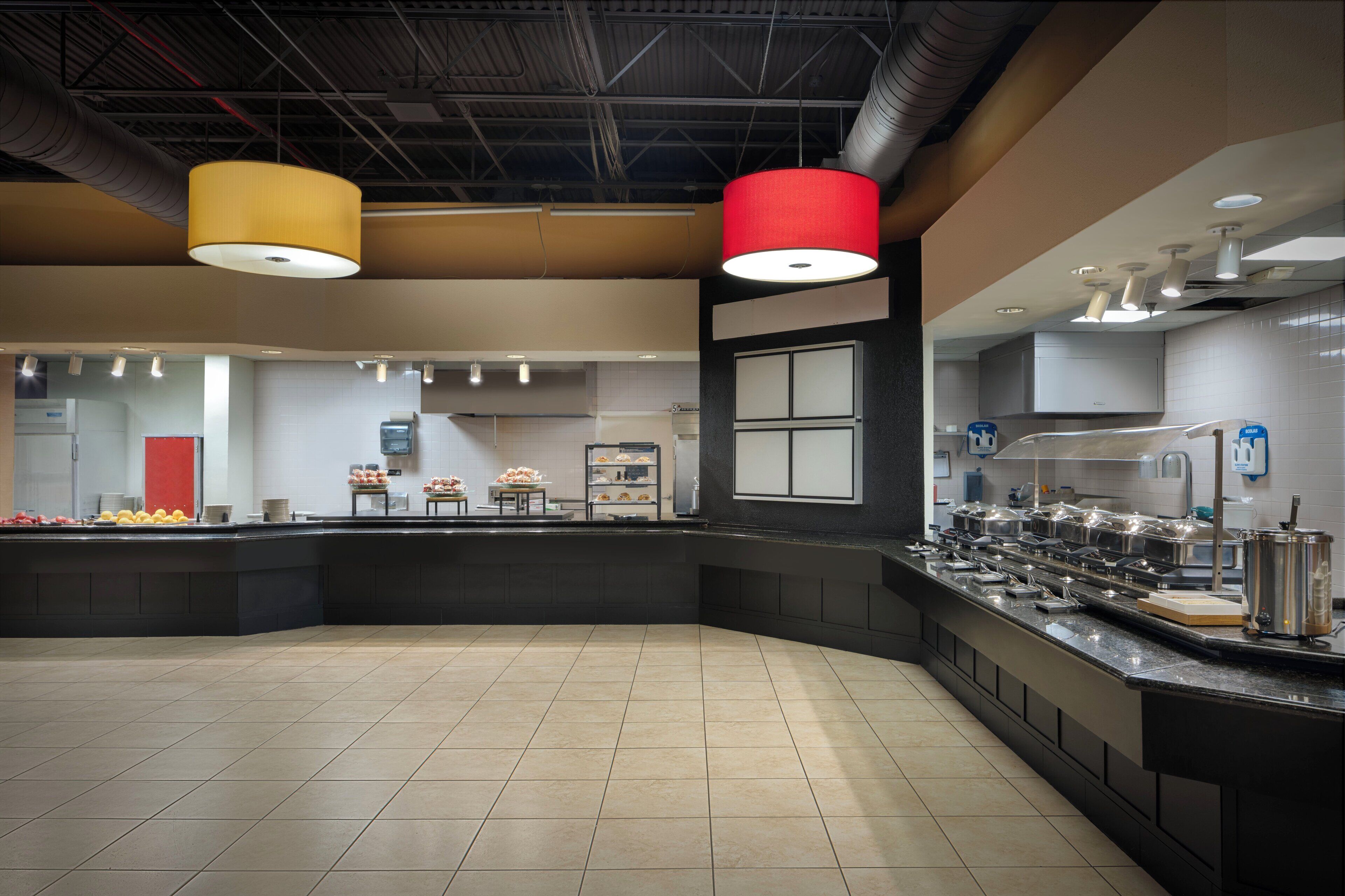 A modern kitchen with a central island, equipped with various appliances and a buffet setup.