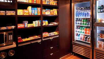 A vending machine stocked with snacks and beverages, a microwave, and a refrigerator.