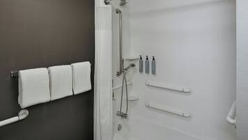 Un baño con bañera, ducha y un toallero con tres toallas.