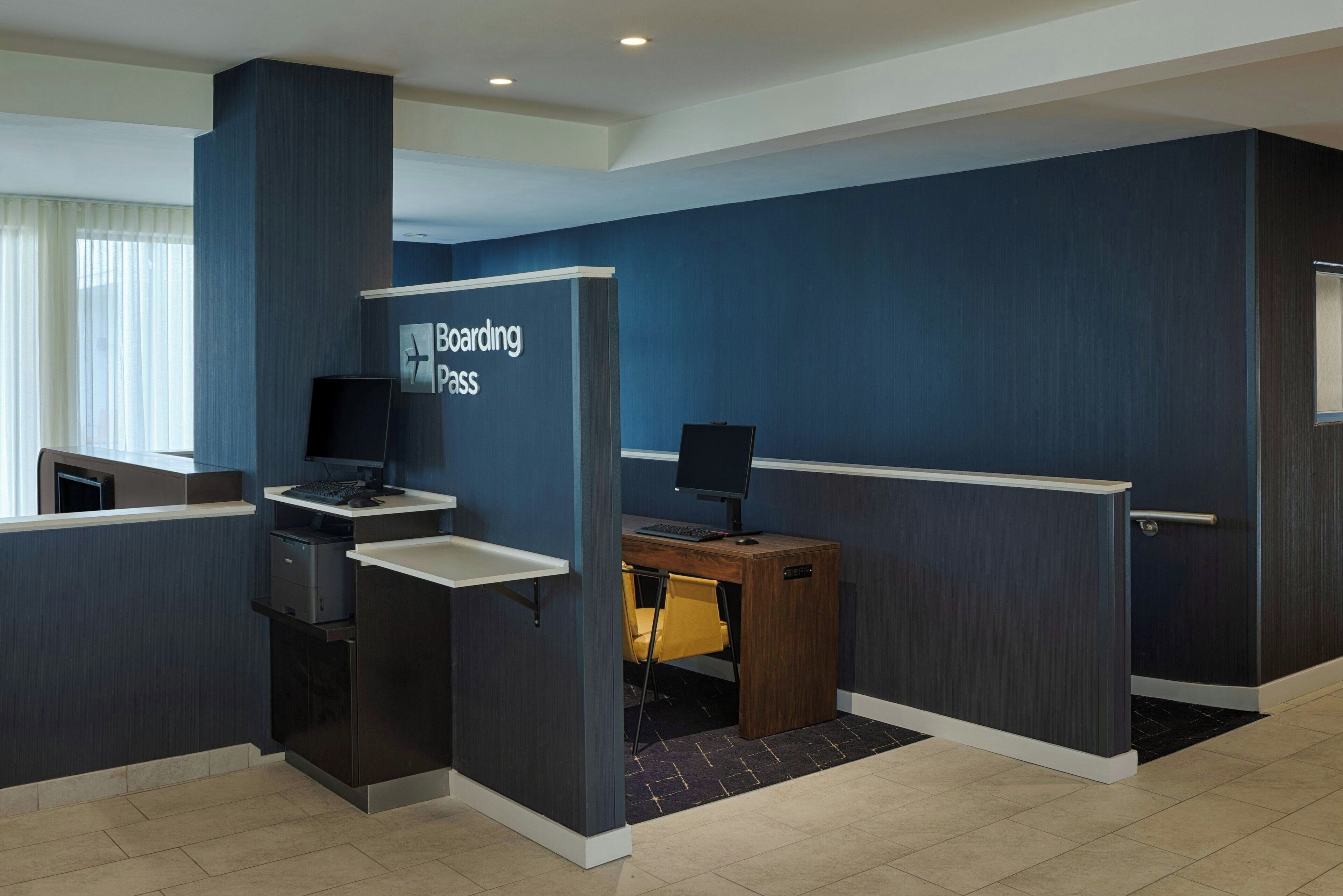 Una moderna reception con una insegna che riporta 'Boarding Pass', un computer e una sedia da scrivania.