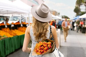Una persona sosteniendo un ramo de flores en un mercado al aire libre.