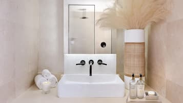 A bathroom with a white sink, mirror, and a decorative vase with pampas grass.