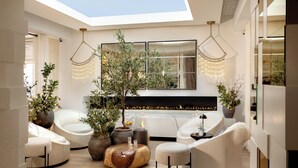 Una sala de estar moderna con tragaluz, muebles blancos y plantas decorativas.