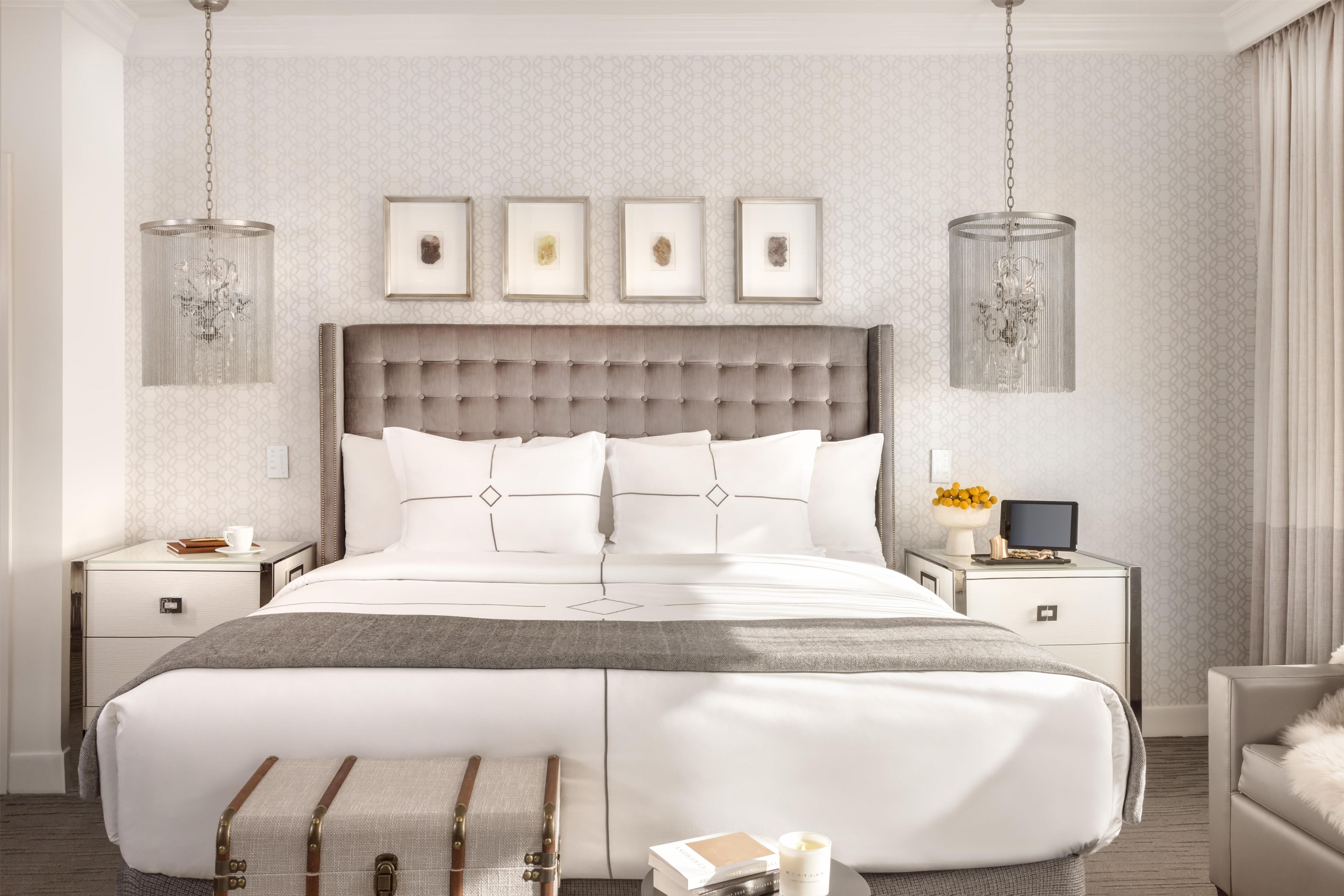 A modern bedroom with a tufted headboard, a large bed, bedside tables, a desk, and a bench.