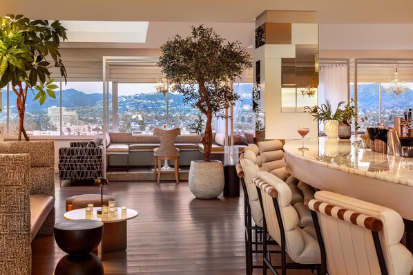A modern lounge area with a bar, seating, and a large tree.