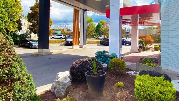 A modern building with a covered entrance, parking lot, and landscaped garden with various plants. - Comfort Inn Kenora (Kenora)