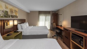 A hotel room with two beds, a desk with a flat-screen TV, a chair, a desk lamp, and a painting on the wall. - Comfort Inn Kenora (Kenora)