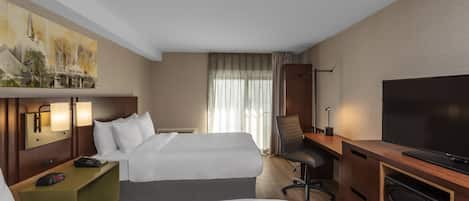 A hotel room with two beds, a desk with a flat-screen TV, a chair, a desk lamp, and a painting on the wall.