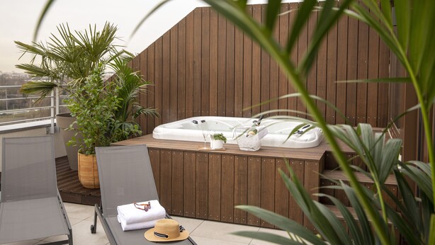 En tagterrasse med jacuzzi, liggestole og plantekasser.