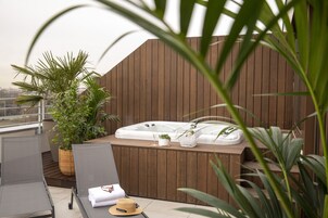 Terraza en la azotea con jacuzzi, sillones de descanso y plantas en macetas.