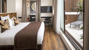 Et hotelværelse med en stor seng, fjernsyn, skrivebord og udsigt til en pool og udendørs område.