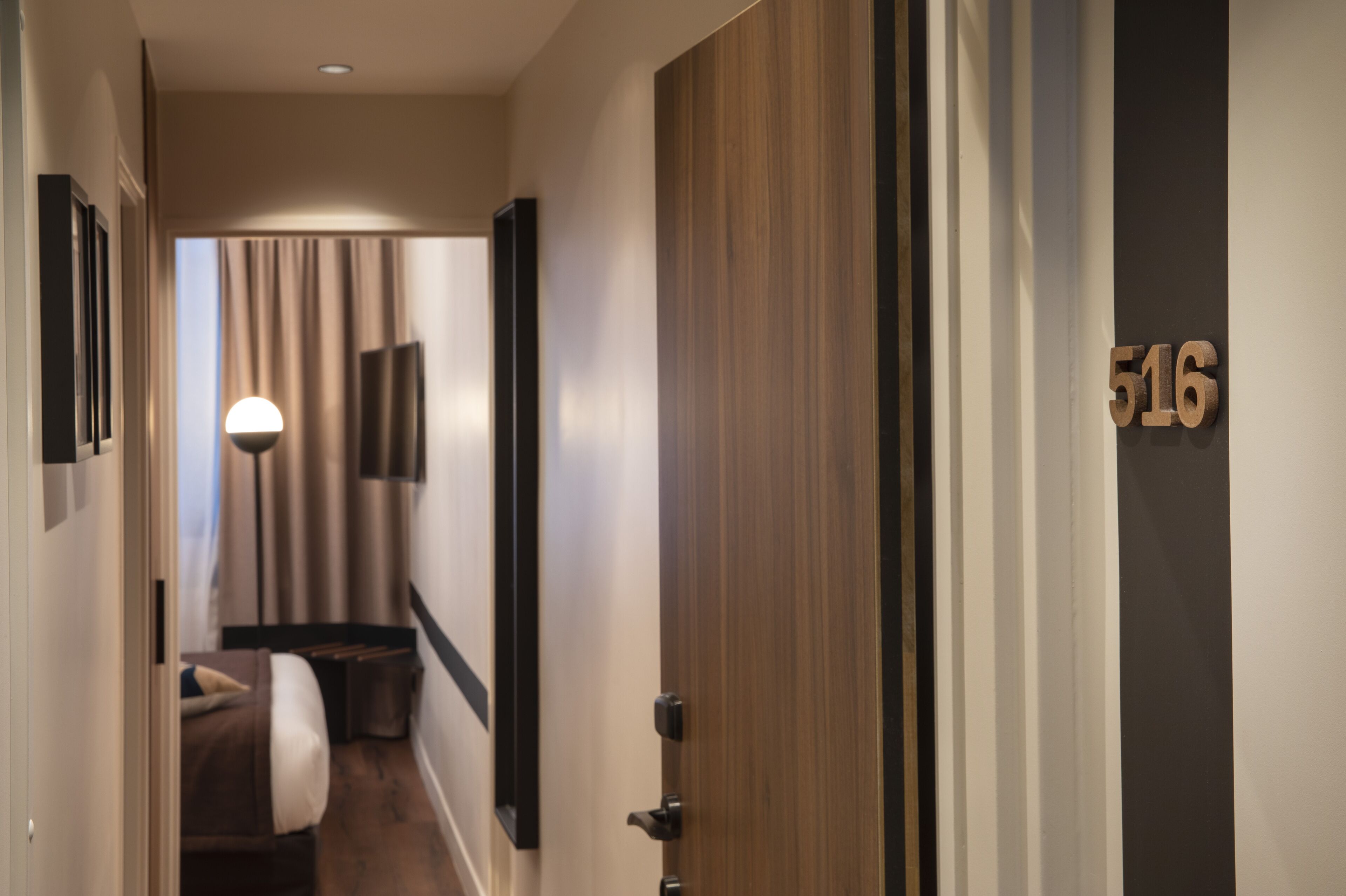 Ein Hotelkorridor mit einem Bett, einer Lampe und einer Tür mit der Nummer 516.