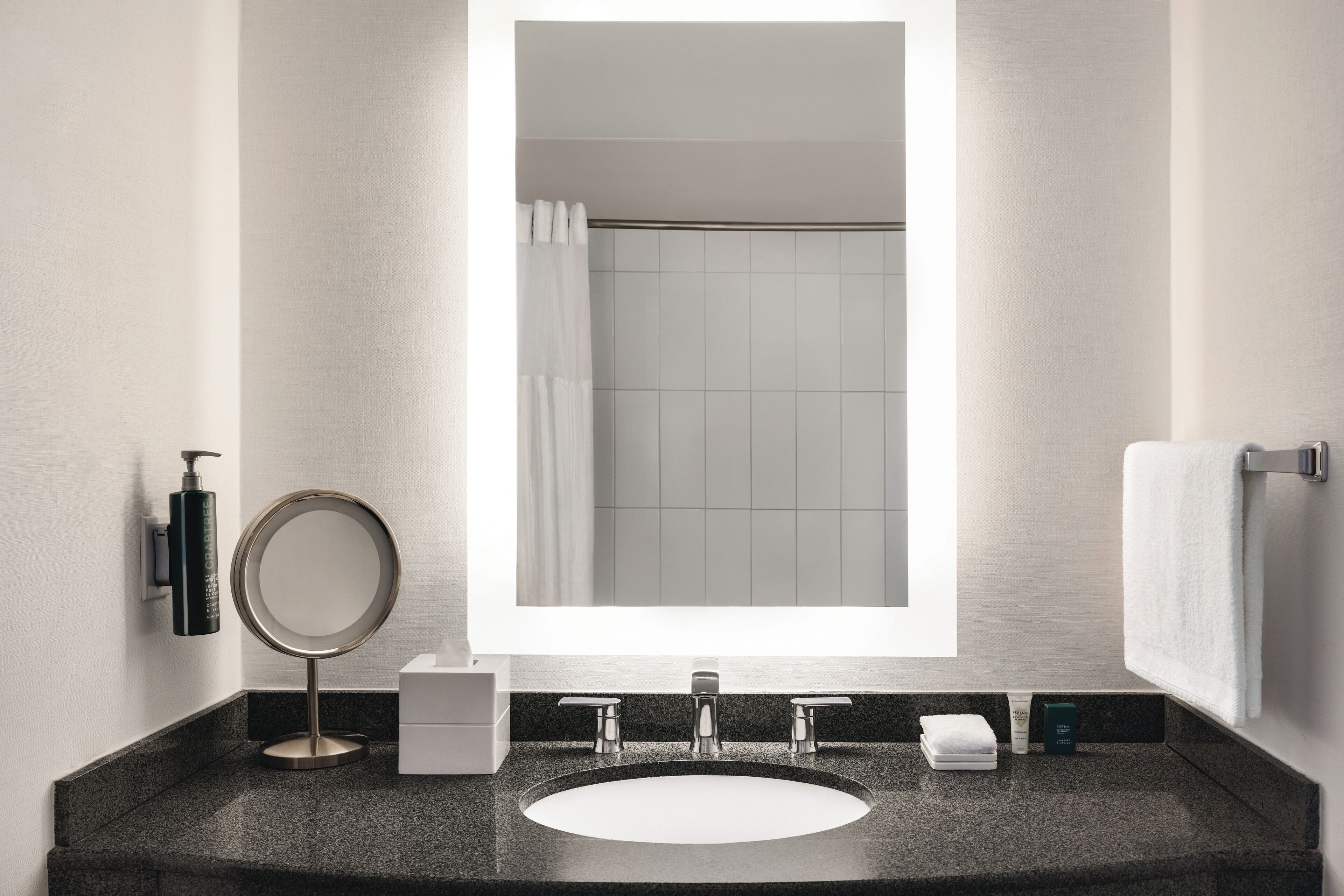 Une salle de bain moderne avec un grand miroir, un lavabo et une douche.